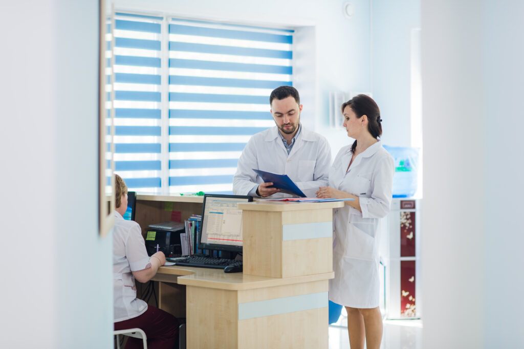 Recepción concurrida en un hospital con doctores y recepcionistas.